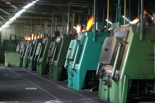 Factory scene with lined up industrial machines blowing flames, metallurgic industry .