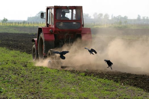 Farmer working the field with tractor in rural landscape.