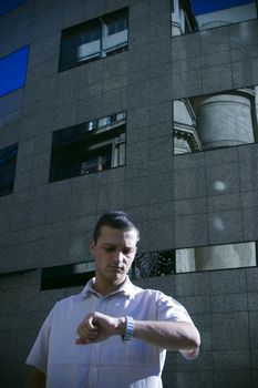 A young business man checks his watch as he is rushed for time.