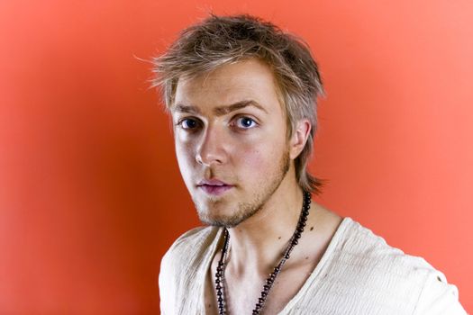 Portrait in horizontal form of a pensive 20 year old man. Isolated on peach colored background.