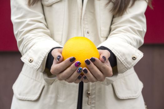 Hands girl with fashionable manicure keep oranges on the street