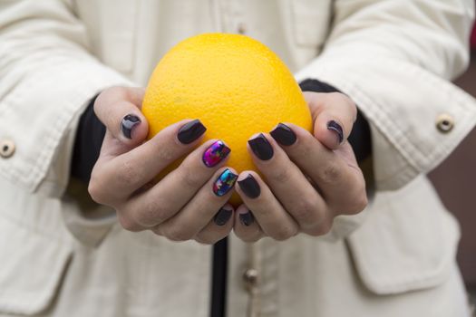 In the hands of a girl with a stylish manicure Orange bright orange