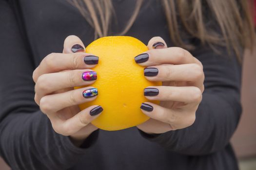 In the hands of a girl with a stylish manicure Orange bright orange