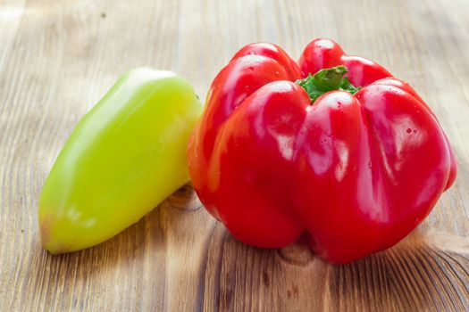 Vegetable still life of two mature red and green peppers on wooden background