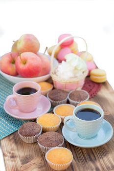 Still life of served coffee cups, macaroon cookies, marshmallows and apples