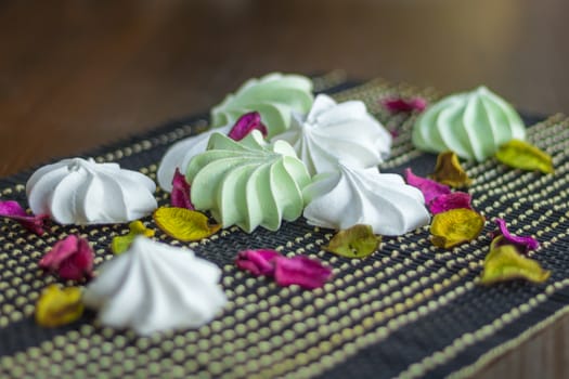 White and green marshmallow dessert composition on black background