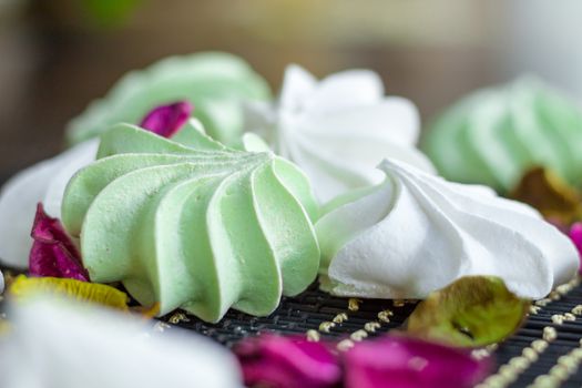 White and green marshmallow dessert composition on black background