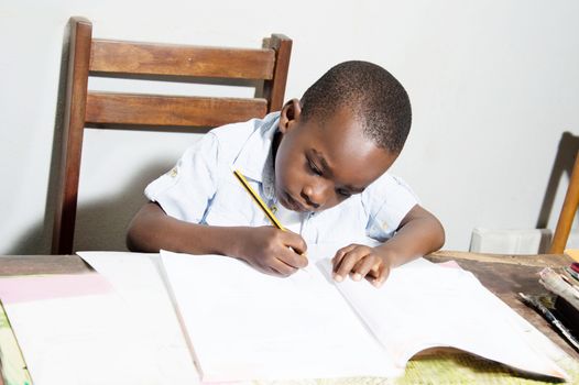 Children studying at home by writing in his daily notebook.