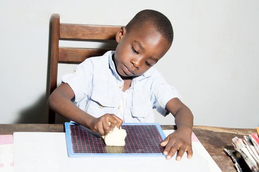 This child cleans his slate with a cloth to use it better.