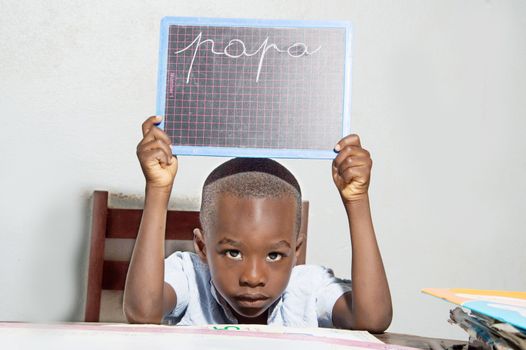 The child learns to write at home. He writes dad and shown to his mother.