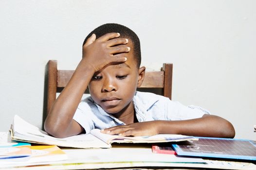 This child is studying with his hand on his forehead.