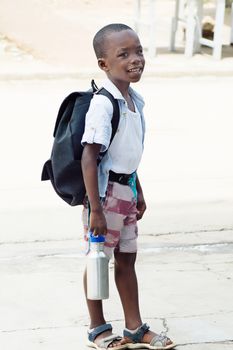 A small schoolboy waiting for a school bus.