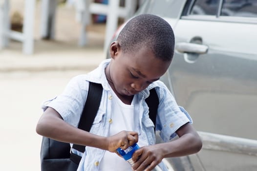 This child opens his bottle containing water because he is thirsty.