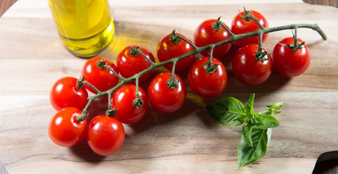 Bunch of cherry tomatoes on a wooden background and oil