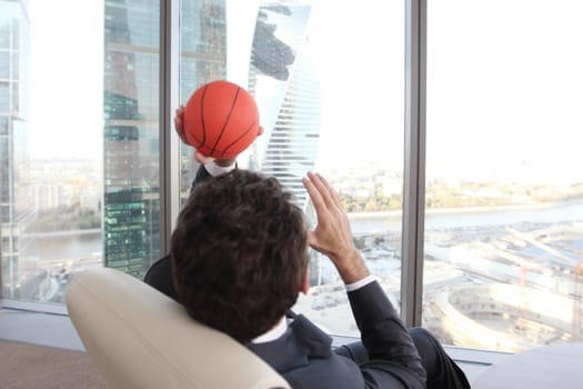 Business man playing with a basketball at the office