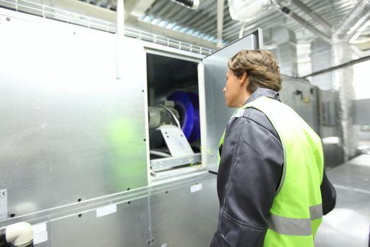 Worker in electrical switchgear room of CNC plant