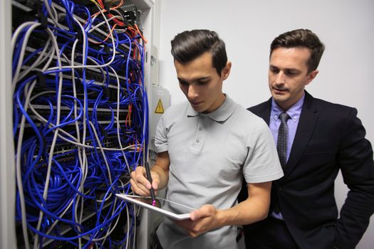 Young engeneer and business man in network server room with digital tablet