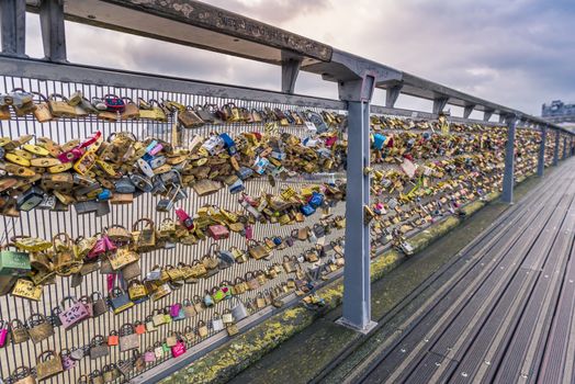 The iron balustrade of the Passerelle Leopold-Sedar-Senghor in Paris, France, filled with locks by tourists to symbolize love and commitment.