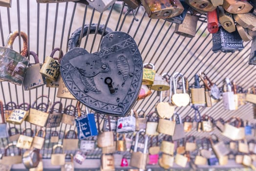 Close up image with an old metallic heart shaped lock, caught on a fence. Suitable for a love concept or background.