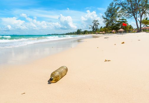 Old plastic bottle on a beautiful tropical beach in Indonesia. Pollution concept.