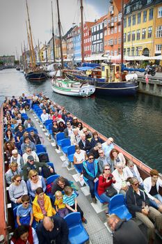 COPENHAGEN, DENMARK - AUGUST 14, 2016: Tourists enjoy and sightseeing in tourist boat at the canal Nyhavn. The boat is loaded with sightseeing tourist people in Copenhagen, Denmark on August 14, 2016.