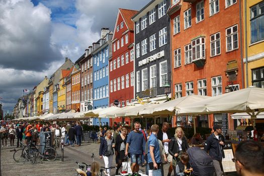 COPENHAGEN, DENMARK - AUGUST 14, 2016: Boats in the docks Nyhavn, people, restaurants and colorful architecture. Nyhavn a 17th century harbour in Copenhagen, Denmark on August 14, 2016.