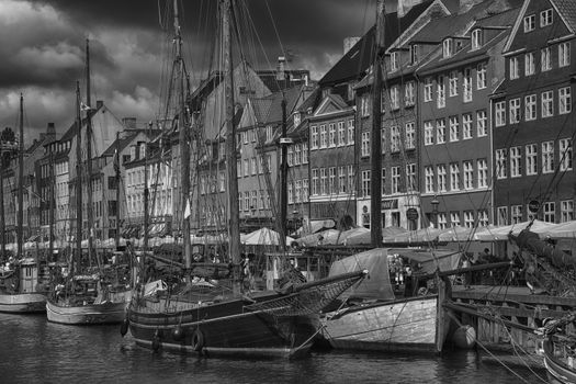 COPENHAGEN, DENMARK - AUGUST 14, 2016: Black and white photo, boats in the docks Nyhavn, people, and colorful architecture. Nyhavn a 17th century harbour in Copenhagen, Denmark on August 14, 2016.