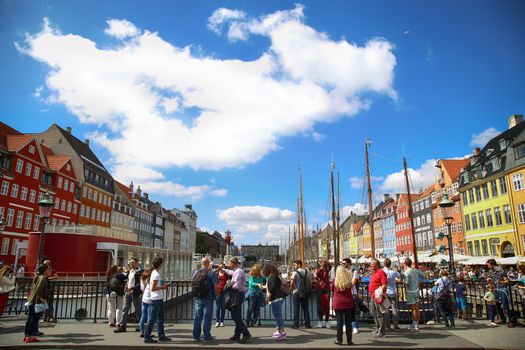 Copenhagen, Denmark – August  15, 2016: Boats in the docks Nyhavn, people, restaurants and colorful architecture. Nyhavn a 17th century harbour in Copenhagen, Denmark