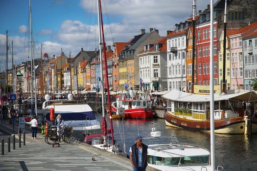 Copenhagen, Denmark – August  15, 2016: Boats in the docks Nyhavn, people, restaurants and colorful architecture. Nyhavn a 17th century harbour in Copenhagen, Denmark