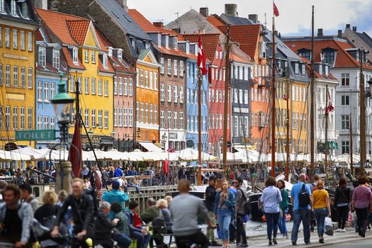 Copenhagen, Denmark – August  14, 2016: Boats in the docks Nyhavn, people, restaurants and colorful architecture. Nyhavn a 17th century harbour in Copenhagen, Denmark