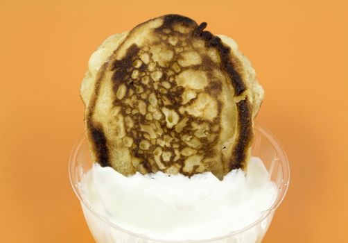 Closeup of a gingerbread pancake with sour cream on a yellow background