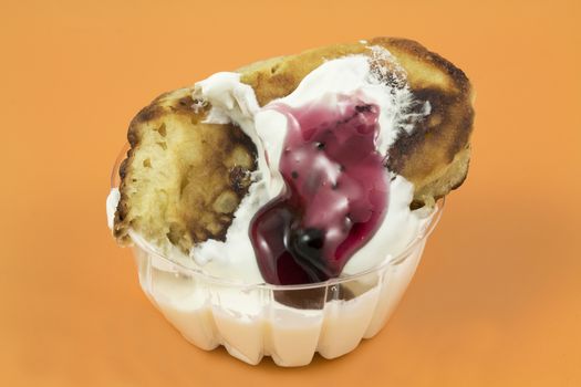 Closeup of a gingerbread pancake with jam in sour cream on a yellow background