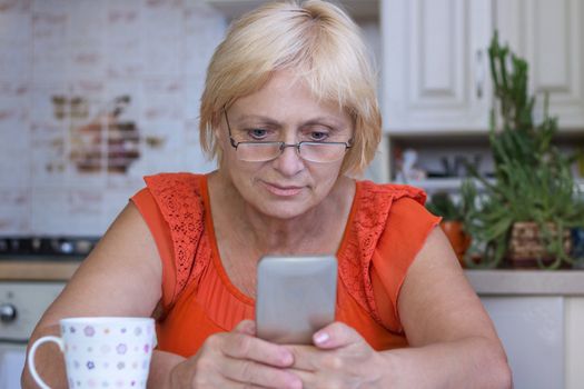 Elderly woman sends sms on mobile phone
