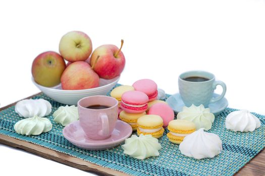 Still life of served coffee cups, macaroon cookies, marshmallows and apples