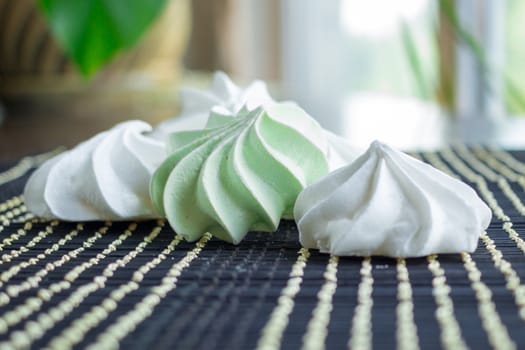 White and green marshmallow dessert composition on black background