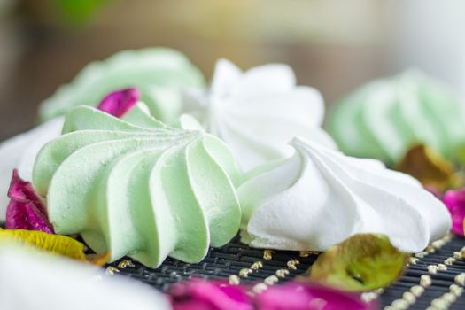 White and green marshmallow dessert composition on black background