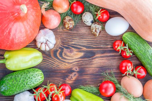 Bright Thanksgiving harvest composition of vegetables onions, cucumbers, peppers pumkin, calabash, tomatoes, garlic, eggs on dark wooden background