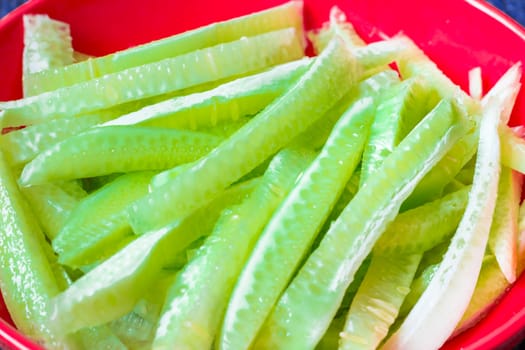 Fresh sliced strips of cucumber on scarlet plate