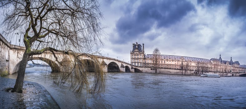 The Pont Royal, Louvre Palace and the river Seine on a rainy day of February, in Paris, France.