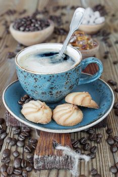 Black coffee in blue vintage cup and cookies on old dark cutting board