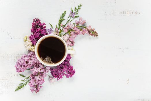 Cup of coffee and different lilac flowers on the wooden background; flat lay, top view