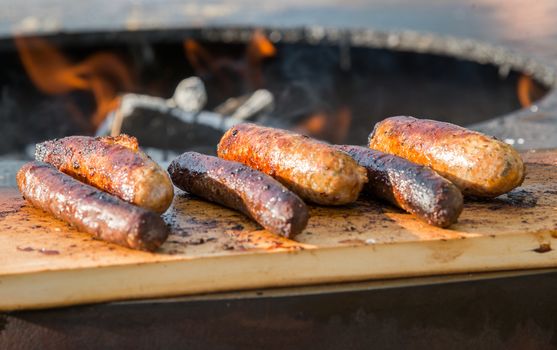 Grilling sausages on cutting board and barbecue grill