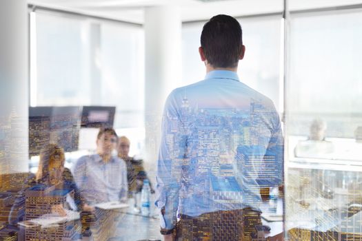 Business man making a presentation at office. Business executive delivering a presentation to his colleagues during meeting or in-house business training. Rear view. Shalow depth of field.