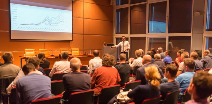 Speaker giving a talk in conference hall at business event. Audience at the conference hall. Business and Entrepreneurship concept.