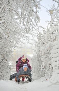 Two cute kids riding sled in winter time