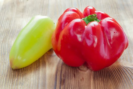 Vegetable still life of two mature red and green peppers on wooden background
