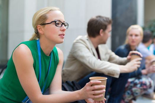 Cheerful colleagues meeting on stairs outdoor for in a quick coffee break. Coffee to go.