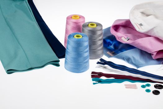 Different tailor's accessories, pants and shirts on a studio background