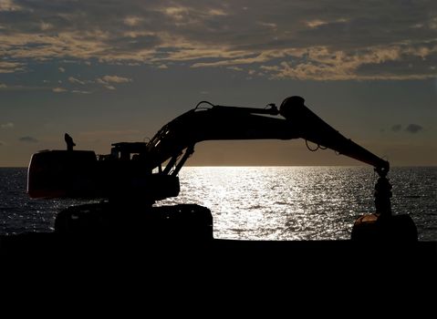 Excavator standing against sun, silhouette image