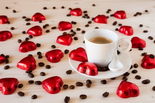Red chocolate hearts, coffee beans and an espresso coffee on a table